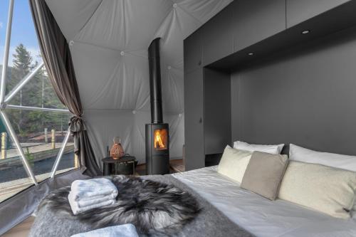 1 dormitorio con 1 cama grande y chimenea en Golden Circle Domes - Glamping Experience en Selfoss