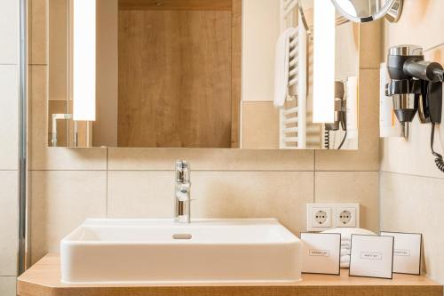 ケルンにあるホテル フランドリッシャー ホフのバスルーム(白い洗面台、鏡付)
