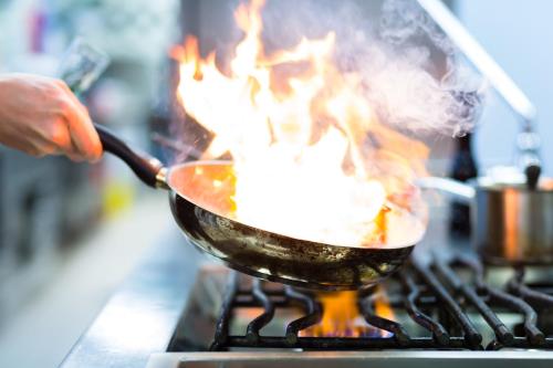 a person cooking food in a wok on a stove at Hotel Terme Venezia in Abano Terme