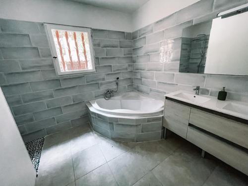 ein weißes Badezimmer mit einer Badewanne und einem Waschbecken in der Unterkunft Demeure du Dragon 5 chambres Piscine- 10 lits - personnes in Saint Jean du Pin