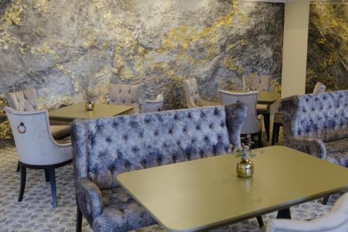a restaurant with tables and chairs and a stone wall at Muller Hotel Boutique & Spa in Galaţi