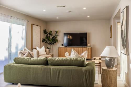 sala de estar con sofá verde y TV en @ Marbella Lane - Vibrant & Chic Designer Home, en Fullerton