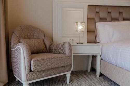 a bedroom with a chair and a desk next to a bed at Muller Hotel Boutique & Spa in Galaţi