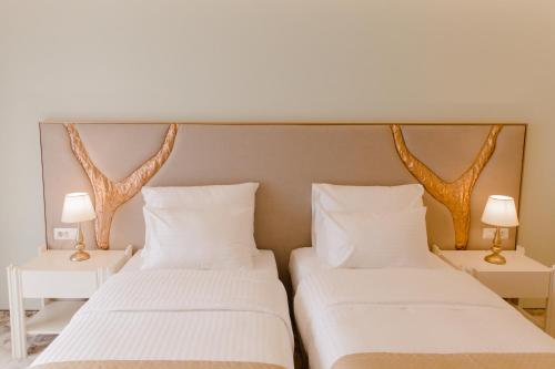 two beds in a room with white sheets and lamps at Muller Hotel Boutique & Spa in Galaţi