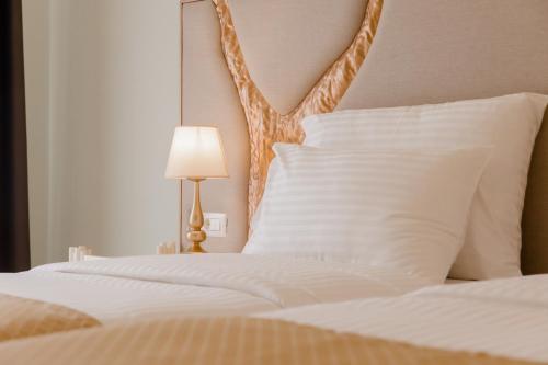 a bedroom with a bed with white pillows and a lamp at Muller Hotel Boutique & Spa in Galaţi