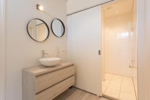 a bathroom with a sink and a mirror on the wall at Hello Zeeland - Appartement Beatrixstraat 29 in Domburg