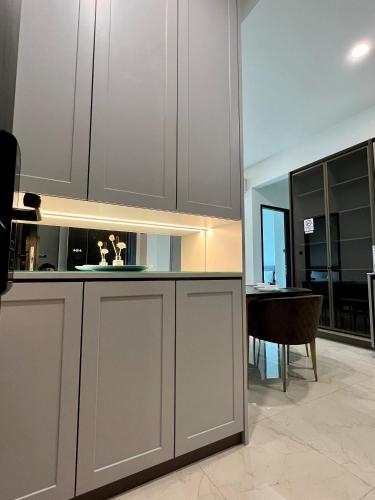 a kitchen with white cabinets and a dining room at Opus Residence KL by EUcation Home in Kuala Lumpur