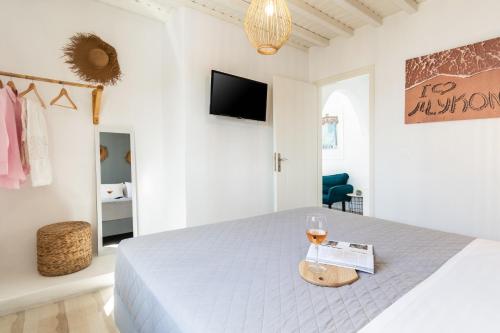 a white bedroom with a bed and a glass of wine at Haka Suites Mykonos Town in Mikonos