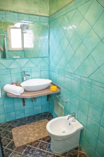 a blue tiled bathroom with a sink and a toilet at Acqua Azzurra in Alghero