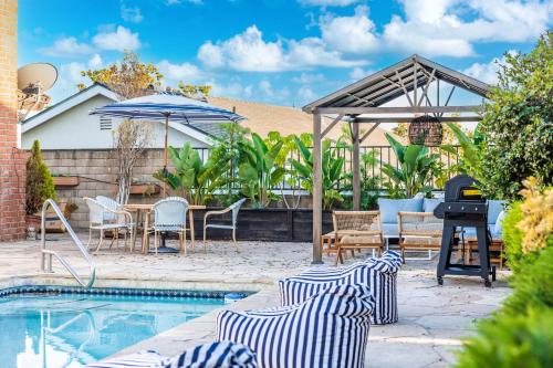 a backyard with a grill and chairs and a pool at @ Marbella Lane - Vibrant & Chic Designer Home in Fullerton