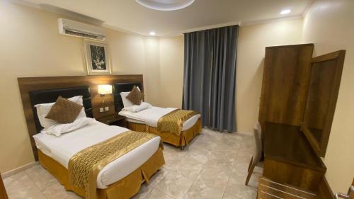 a hotel room with two beds and a television at Almasakin Alfakhira in Al Shafa