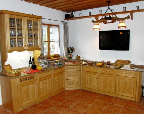 cocina con armarios de madera y TV de pantalla plana. en Haus Christoph, en Bad Wiessee