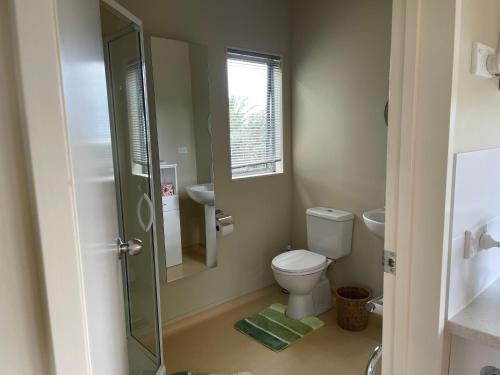 a bathroom with a toilet and a glass shower at Chalet Cullen, in Mangawhai