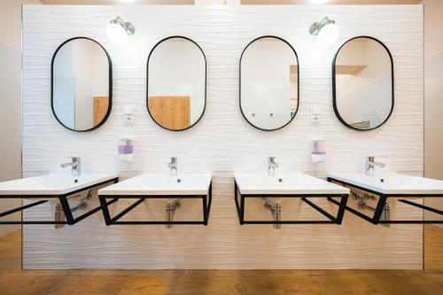 a bathroom with three sinks and mirrors on a wall at Luma Terra Prague Hostel in Prague