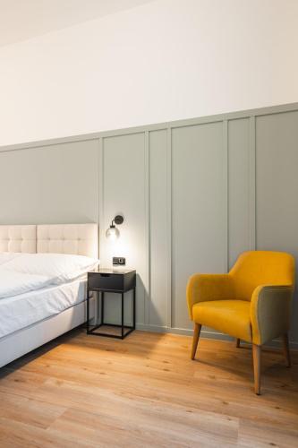 a bedroom with a bed and a yellow chair at Luma Terra Prague Hostel in Prague