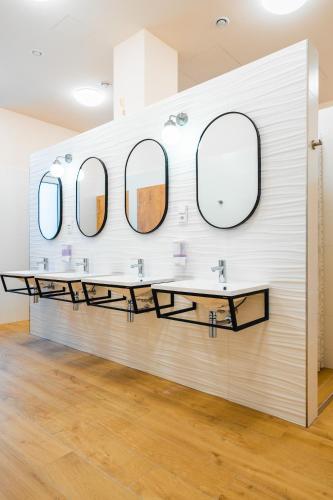 a bathroom with three sinks and mirrors on a wall at Luma Terra Prague Hostel in Prague