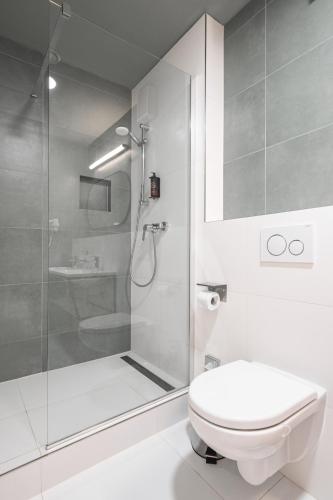 a white bathroom with a shower and a toilet at Luma Terra Prague Hostel in Prague