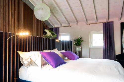 a bedroom with a large white bed with purple pillows at Atena Dolce Vita in Brescia