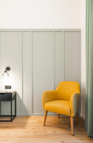 a yellow chair in a room with a table at Luma Terra Prague Hostel in Prague