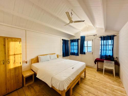 a bedroom with a large bed with blue curtains at Cocos Beach Resort in Palolem