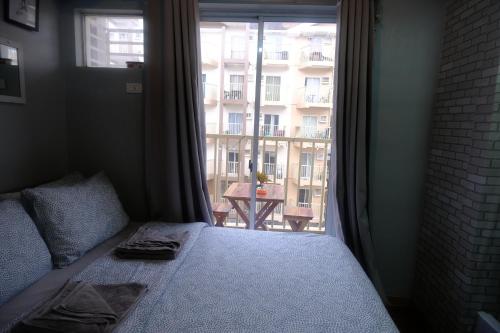a bedroom with a bed and a large window at Homey 1-bedroom Condo Baguio City Moldex in Baguio