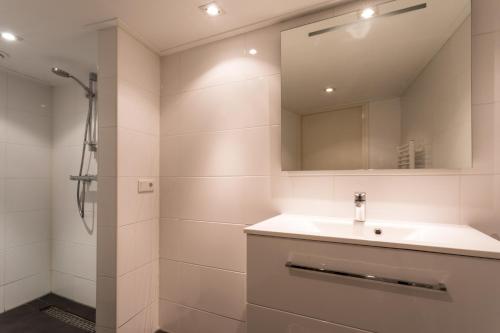 ein weißes Bad mit einem Waschbecken und einer Dusche in der Unterkunft Hello Zeeland - Vakantiehuis Beatrixstraat 29A in Domburg