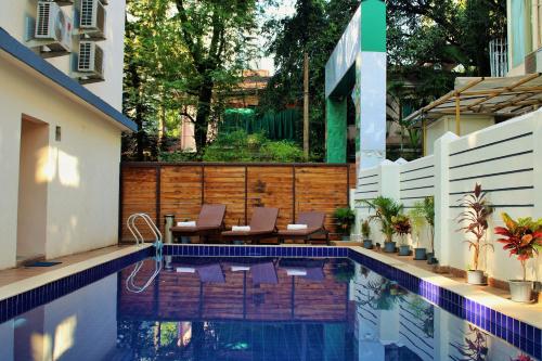a swimming pool with chairs next to a house at Wotel Calangute Goa in Calangute