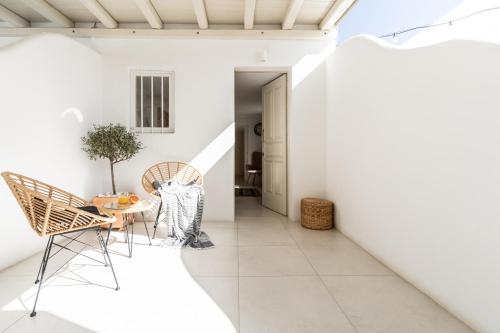 Cette chambre est dotée de murs blancs, d'une table et de chaises. dans l'établissement Haka Suites Mykonos Town, à Mykonos