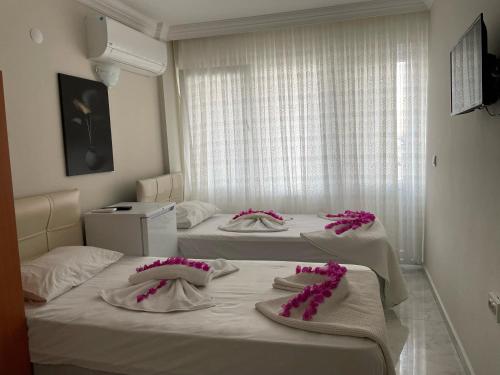 迪迪姆的住宿－THE BEACH OTEL DİDİM，客房内的两张床,上面有粉红色的鲜花
