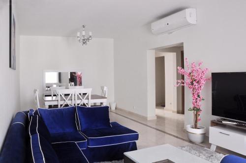 ein Wohnzimmer mit einem blauen Sofa und einem TV in der Unterkunft Axxodia Mivida Boulevard New cairo in New cairo