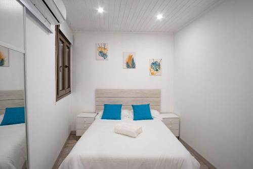 um quarto branco com uma cama e almofadas azuis em Casa Antequeruela em Toledo