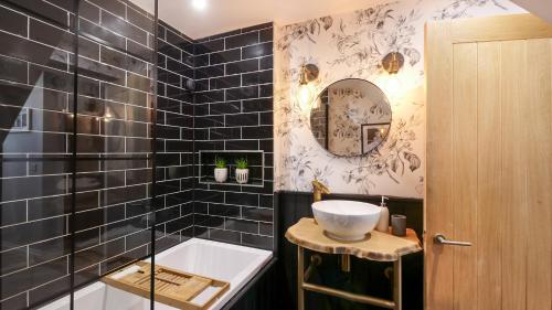 a bathroom with a sink and a tub and a mirror at Nala's Nest in Hexham