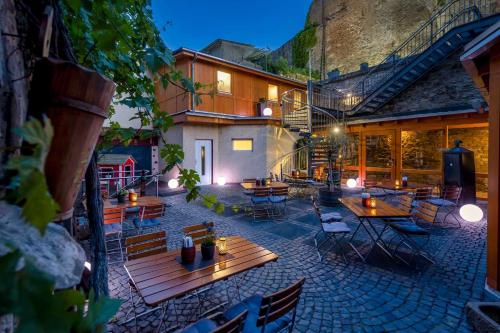 un patio extérieur avec des tables et des chaises en bois la nuit dans l'établissement AKZENT Hotel Restaurant Roter Ochse Rhens bei Koblenz, à Rhens