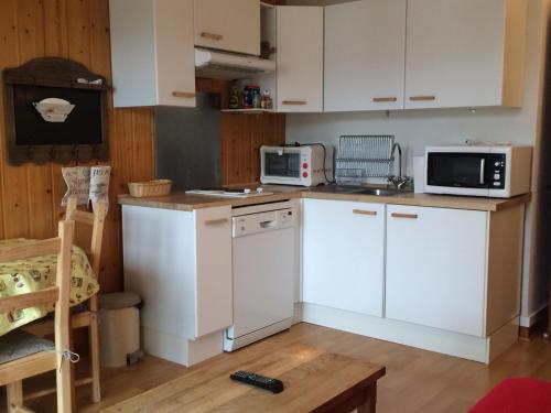 une cuisine avec des armoires blanches et des appareils électroménagers blancs dans l'établissement Charmant 2 Pièces en Cœur de Village, Proche Piscine et Patinoire - 5 Pers, 46m² - FR-1-515-89, à Villard-de-Lans
