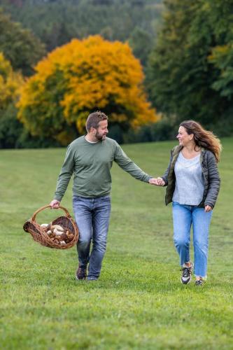 a man and woman walking with a basket of mushrooms at Manoir de Sterpigny, château-ferme 17ème siècle gîte la Tour in Gouvy