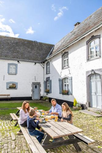 a group of people sitting around a picnic table at Manoir de Sterpigny, château-ferme 17ème siècle gîte la Tour in Gouvy