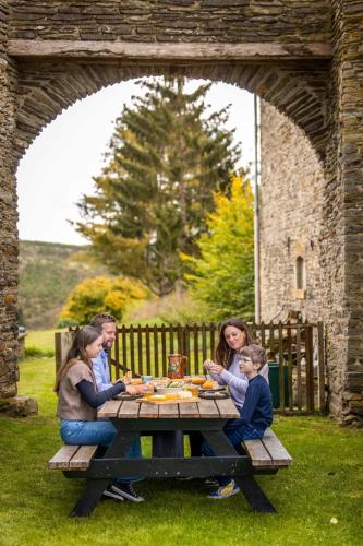 a group of people sitting around a picnic table at Manoir de Sterpigny, château-ferme 17ème siècle gîte la Tour in Gouvy