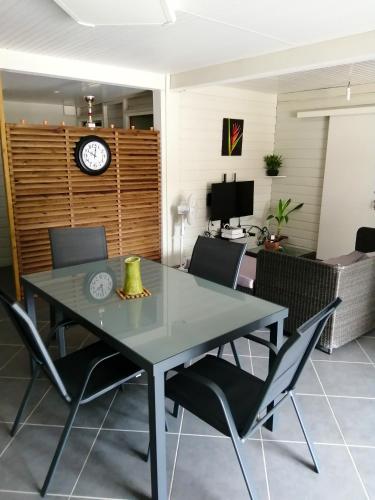 a dining room with a table and chairs and a clock at Appartement charmant à Rivière-Pilote avec piscine partagéeB in Rivière-Pilote