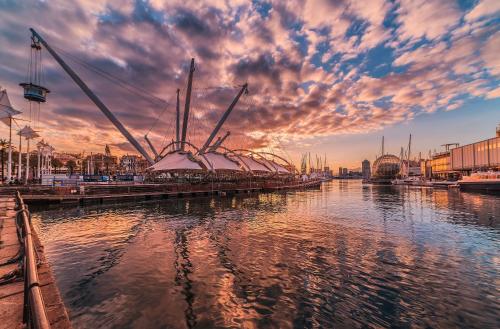 a sunset over a river with a bridge in the water at Hotel Astoria in Genova