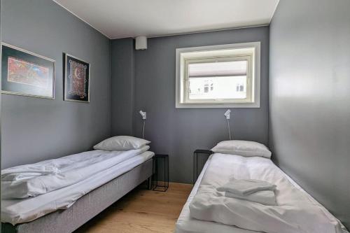two beds in a room with a window at Modern easy-living apartment in nice neighborhood in Tromsø