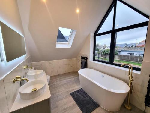 a bathroom with a large white tub and a sink at Brand New, Stunning Beachside House in Seasalter