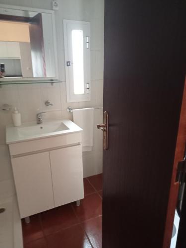 a white bathroom with a sink and a door at Casas da Nazaré2 in Ponte de Lima