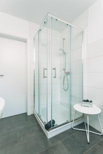 a glass shower in a bathroom with a table at Das Schlafgut Dessau in Dessau