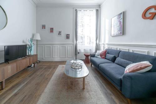 een woonkamer met een blauwe bank en een tv bij Résidence Epinat II - Appartements centre - Parking in Vichy