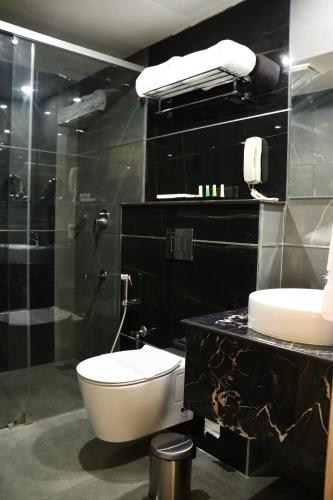 a black bathroom with a toilet and a sink at Capital Park Residency in Trivandrum
