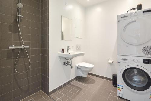 W łazience znajduje się toaleta, umywalka i pralka. w obiekcie Stylish 2BR w Private Balcony in CPH City Centre w Kopenhadze