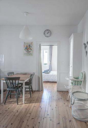 une salle à manger avec une table, des chaises et une horloge dans l'établissement Résidence Epinat II - Appartements centre - Parking, à Vichy