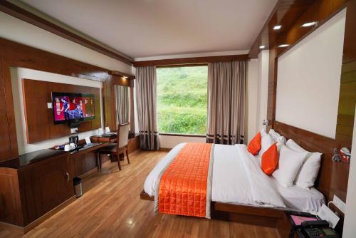 a hotel room with a bed and a desk and a television at Hotel The Twin Towers in Shimla