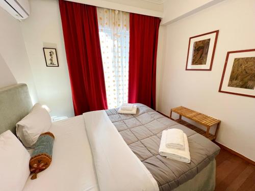 Schlafzimmer mit einem Bett und einem Fenster mit roten Vorhängen in der Unterkunft A Stroll to the Acropolis - By Athenian Homes in Athen