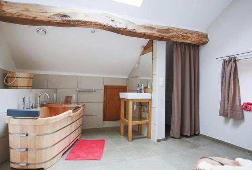 ein Badezimmer mit einer Holzbadewanne und einem Waschbecken in der Unterkunft Coeur de Boeur in Houffalize